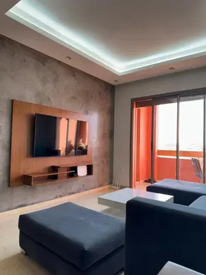 a living room with a couch and a tv on a wall at Appartement de luxe avec piscine et parking gratuit in Marrakech