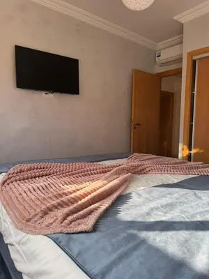 a bedroom with a bed with a flat screen tv on the wall at Appartement de luxe avec piscine et parking gratuit in Marrakech