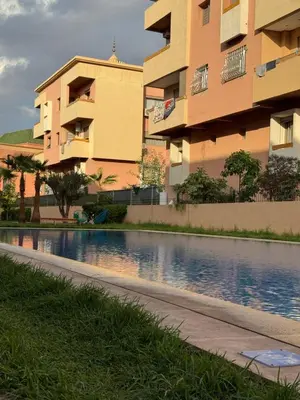 a building next to a swimming pool next to a building at Appartement de luxe avec piscine et parking gratuit in Marrakech