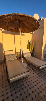 two beds under an umbrella on a floor at Riad Kasbah 82 in Marrakech
