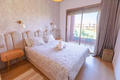a bedroom with a large bed and a large window at Premium Apartment in Marrakech Argan Golf Residence with pool & WiFi in Marrakech