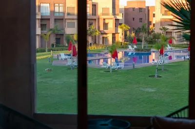 a view of a swimming pool from a window at Premium Apartment in Marrakech Argan Golf Residence with pool & WiFi in Marrakech