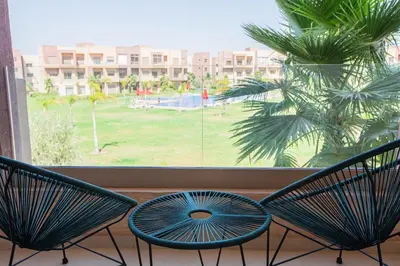 two chairs and a table in front of a window at Premium Apartment in Marrakech Argan Golf Residence with pool & WiFi in Marrakech