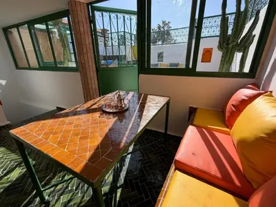a table and a chair in a room with windows at La Douiria Zaouia in Marrakech