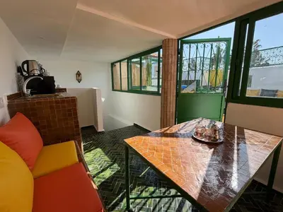 a room with a table and a couch and windows at La Douiria Zaouia in Marrakech
