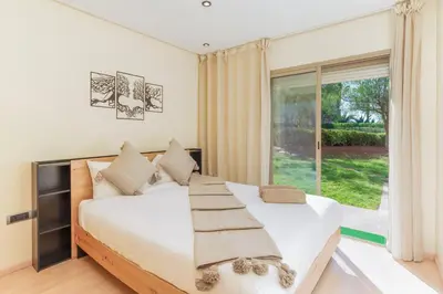 a bedroom with a large bed and a large window at Stylish Flat, Pool, Garden & Fast Wi-Fi in Marrakech