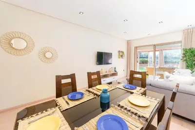 a dining room with a table and chairs and a living room at Stylish Flat, Pool, Garden & Fast Wi-Fi in Marrakech