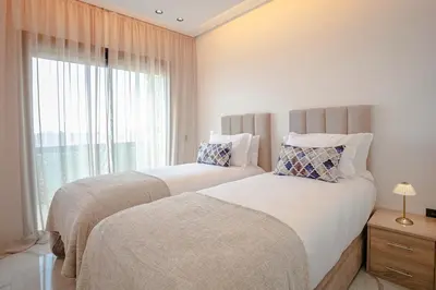 two beds in a bedroom with a window at The Blue Harmony - Hivernage Marrakech in Marrakech
