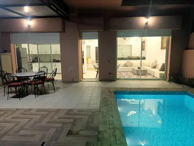 a swimming pool in a house with a table and chairs at Friendly family home in a peaceful location in Marrakech