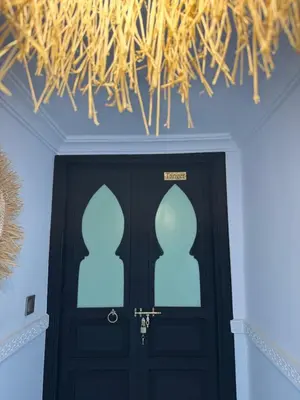 a room with a black door with a straw ceiling at Riad Douha in Marrakech