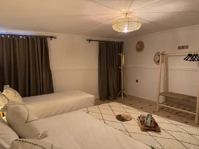 a bedroom with two beds and a chandelier at Riad Douha in Marrakech