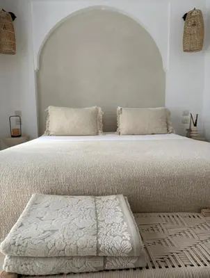 a white bedroom with a large white bed with a bench at Riad Darmoon in Marrakech
