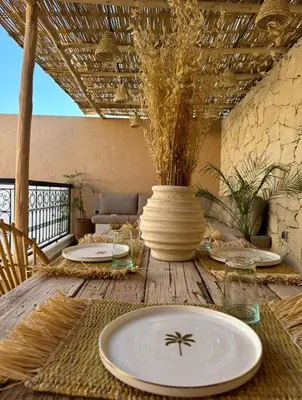 a wooden table with plates and a vase on it at Riad Darmoon in Marrakech