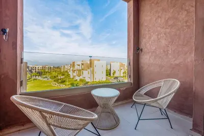 two chairs and a table on a balcony with a window at Comfy Flat 2 BedRooms-Argan Golf Atlas View in Marrakech