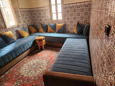 a living room with blue couches and a rug at Dar Damana in Marrakech