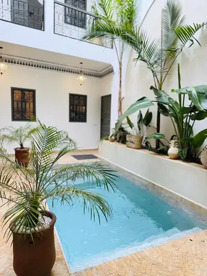 a swimming pool with palm trees in a house at Riad Sumud in Marrakech