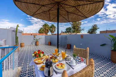 a table with food on a patio with an umbrella at Riad Les Secrets De Marrakech in Marrakech