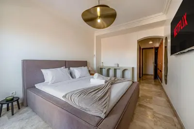 a bedroom with a large bed with white sheets at Luxury Flat Private Rooftop & Heated Pool Guéliz in Marrakech