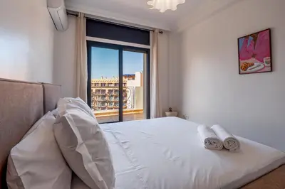 a bedroom with a white bed with a large window at Luxury Flat Private Rooftop & Heated Pool Guéliz in Marrakech