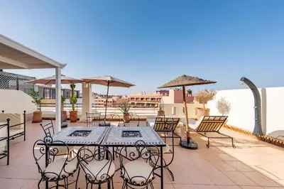 a patio with a table with chairs and umbrellas at Luxury Flat Private Rooftop & Heated Pool Guéliz in Marrakech
