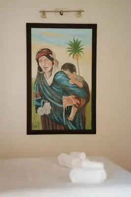 a painting of a woman holding a child on a wall at Cozy Quiet Traditional Apartment in Dar Caïd Layadi