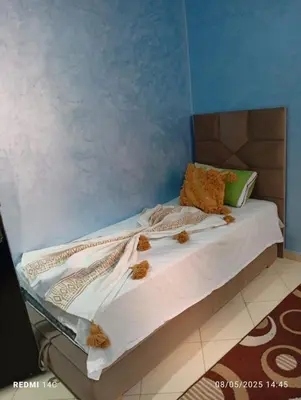 a bed in a room with a blue wall at Appartement familial à Marrakech in Marrakech