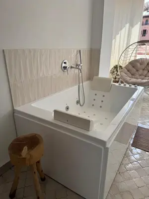 a white bath tub with a shower and a stool at Sublime Appartement JACCUZi privé piscine in Marrakech