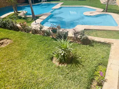 a swimming pool in a yard next to a grass field at Sublime Appartement JACCUZi privé piscine in Marrakech