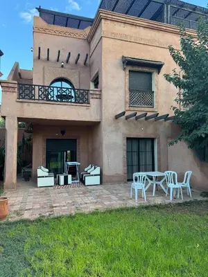 a house with a patio with a table and chairs at Appartement atlas golf ressort in Marrakech