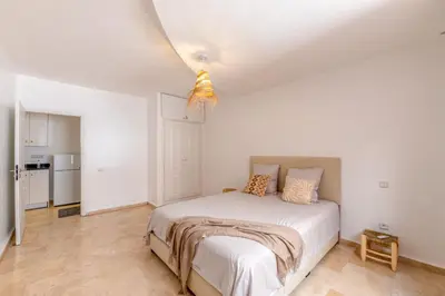 a white bedroom with a bed and a kitchen at Appartement moderne trés securisé a gueliz au centre ville in Marrakech