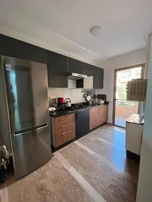 a kitchen with a stainless steel refrigerator and wooden cabinets at Appartement moderne 5 min au centre de ville proche du gueliz in Marrakech