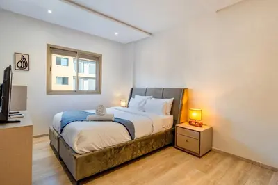 a bedroom with a bed and a window and a television at Sunny Luxe 2BR Heaven Apt Wi-Fi, Balcony & Pool in Marrakech