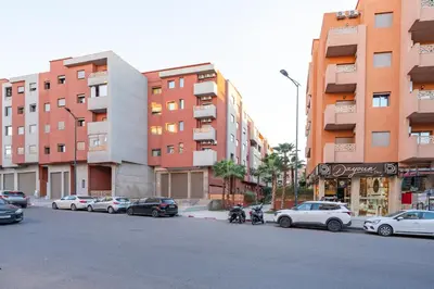 a street with cars parked in front of tall buildings at Sunny Luxe 2BR Heaven Apt Wi-Fi, Balcony & Pool in Marrakech
