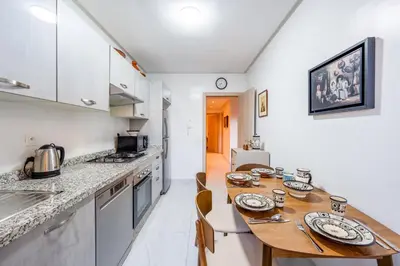 a kitchen with a wooden table in a room at Sunny Luxe 2BR Heaven Apt Wi-Fi, Balcony & Pool in Marrakech