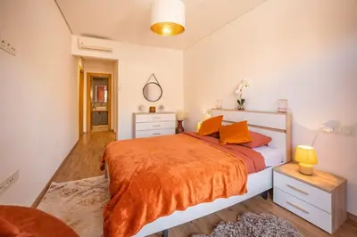 a bedroom with a large bed with an orange blanket at Modern Hivernage Appt New 2-BR w Pool & Terrace in Marrakech