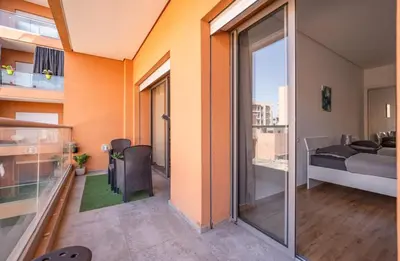 a room with a balcony with a bed and a glass door at Modern Hivernage Appt New 2-BR w Pool & Terrace in Marrakech