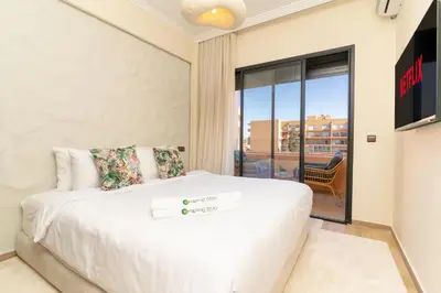 a bedroom with a white bed and a balcony at Luxury Apartment Hivernage 5 minutes from Jemaa El Fna in Marrakech