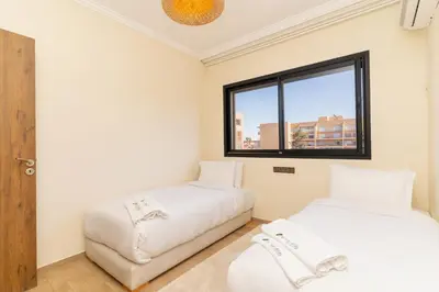 two beds in a room with a window at Luxury Apartment Hivernage 5 minutes from Jemaa El Fna in Marrakech