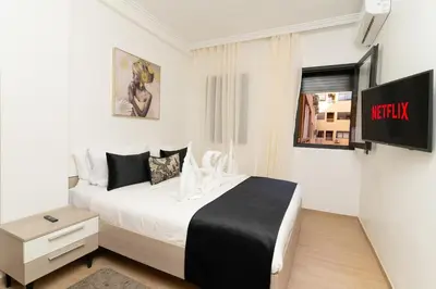 a bedroom with a white bed and a tv at Studio Hivernage 2 munit a la gare in Marrakech