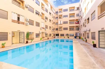 a swimming pool in the courtyard of a apartment building at Studio Hivernage 2 munit a la gare in Marrakech