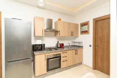 a kitchen with a stainless steel refrigerator and wooden cabinets at Studio Hivernage 2 munit a la gare in Marrakech