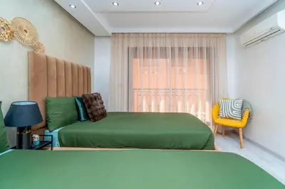a bedroom with two green beds and a yellow chair at Prestigious Duplex in the Center of Guéliz in Marrakech