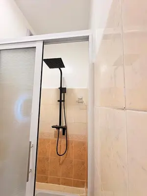 a shower in a bathroom next to a glass door at A haven of light & sweetness in Marrakech