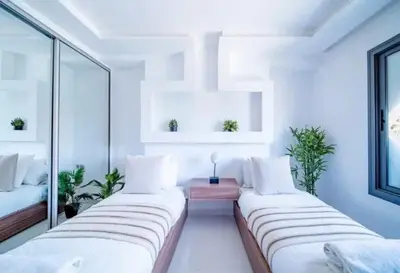 two beds in a room with white walls and windows at Appartement luxe hivernage in Marrakech