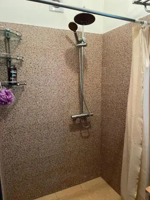 a shower in a bathroom with a tiled wall at Appartement confortable près de l'aéroport in Marrakech
