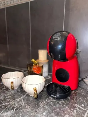 a red coffee maker sitting next to two white bowls at Appartement confortable près de l'aéroport in Marrakech