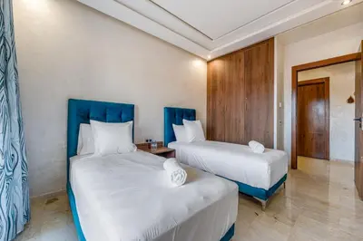 two beds in a room with blue headboards at Stylish Apartment with Balcony view & Free Parking in Marrakech