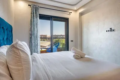 a bedroom with a large white bed with a window at Stylish Apartment with Balcony view & Free Parking in Marrakech