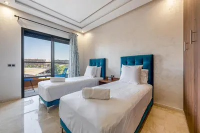 two beds in a room with a window at Stylish Apartment with Balcony view & Free Parking in Marrakech