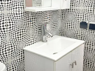 a bathroom with a sink and black and white tiles at Havre de calme - Cour & 2 chambres in Marrakech
